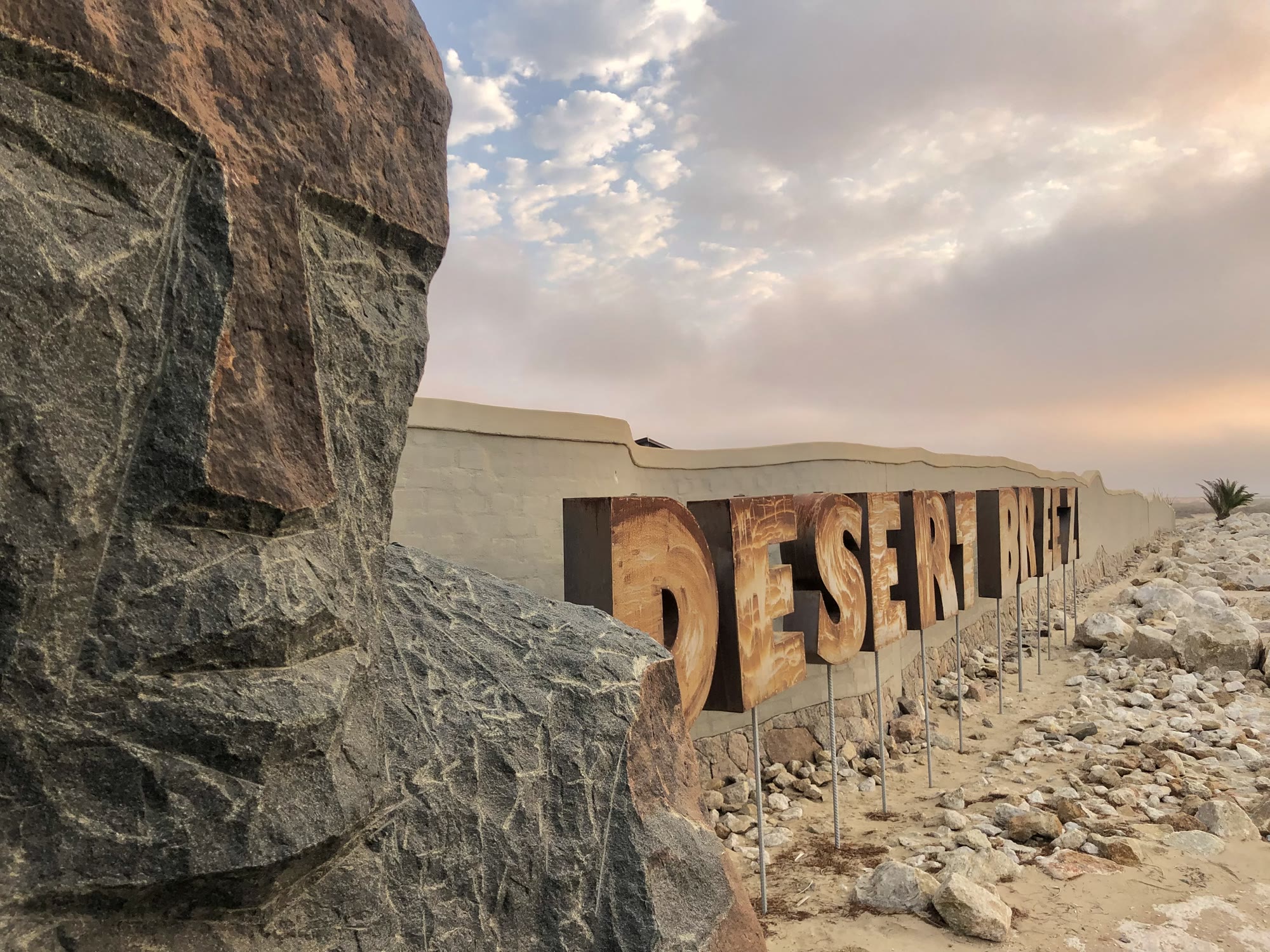 Knut Hünecke sculpture and Desert Breeze sign beneath a desert sky