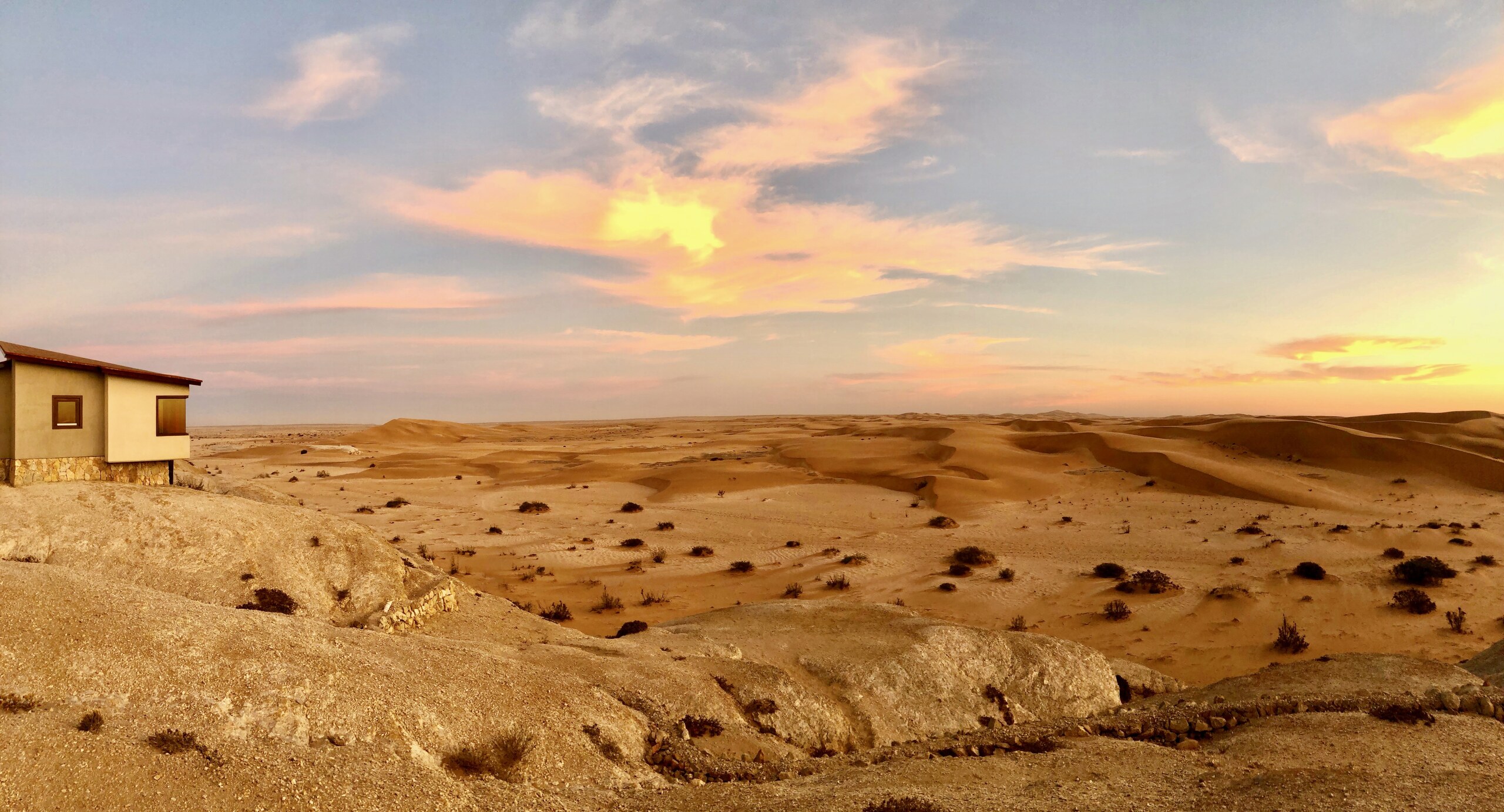Desert Breeze bungalow and Namib dunes beneath a sunset sky