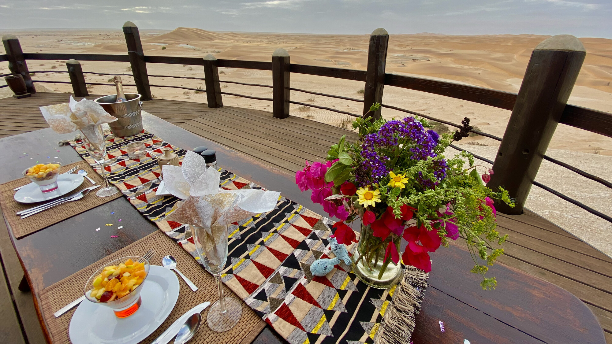 Terrace table set with colourful flowers above the dunes