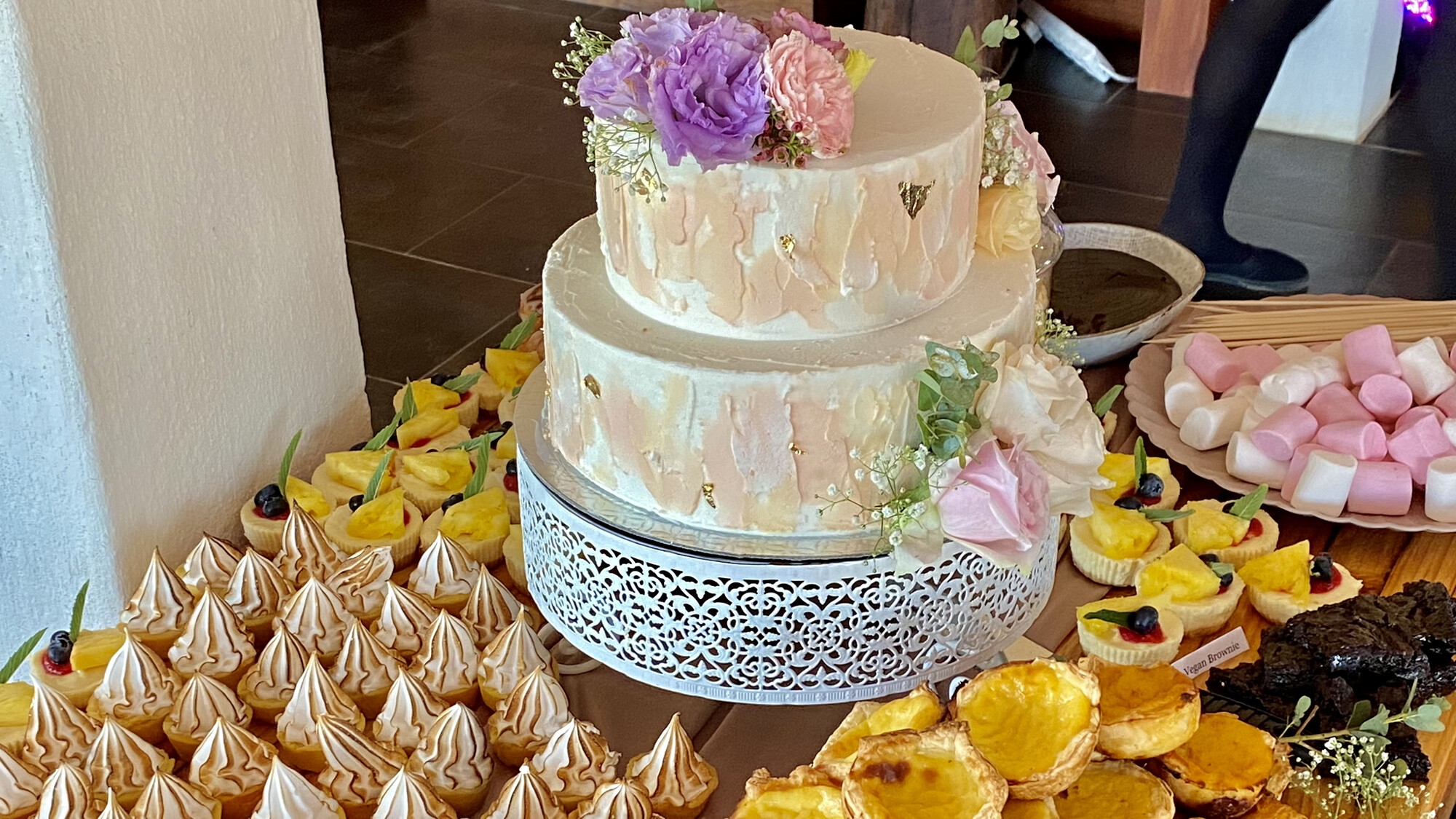 Floral celebration cake surrounded by sweet treats